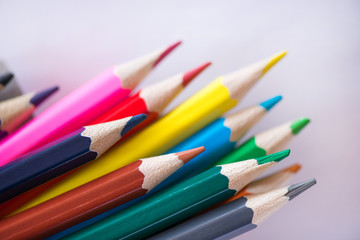 Pile of sharp coloured drawing pencils on table. Rainbow colors  red, yellow, blue, green, purple. Concept of art, crafts and kids having fun