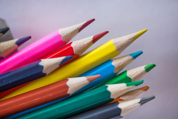 Pile of sharp coloured drawing pencils on table. Rainbow colors  red, yellow, blue, green, purple. Concept of art, crafts and kids having fun
