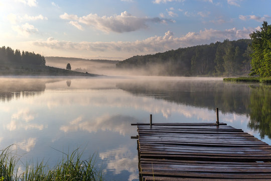sunrise over the foggy river with a wooden pier