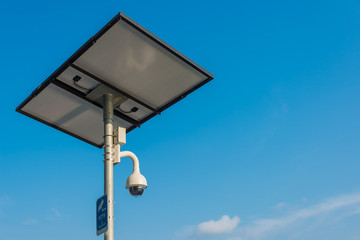 Modern CCTV camera with Solar cell panel charging energy on the metal pole concept or surveillance and monitoring with blue sky background