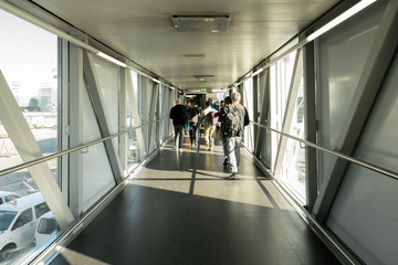 Rear view of an Airline Passengers in the airport bridge, Jet bridge where passengers connect with the plane. 
 airport terminal. 