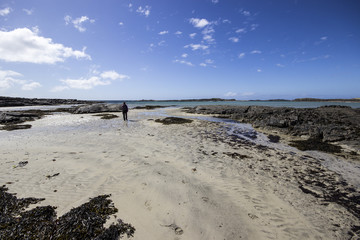 figure walking along a white sand beach