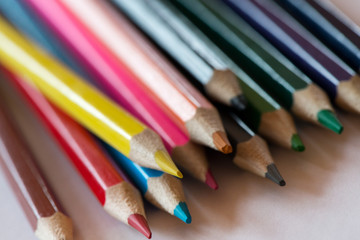 Pile of sharp coloured drawing pencils on table. Rainbow colors  red, yellow, blue, green, purple. Concept of art, crafts and kids having fun
