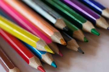 Pile of sharp coloured drawing pencils on table. Rainbow colors  red, yellow, blue, green, purple. Concept of art, crafts and kids having fun
