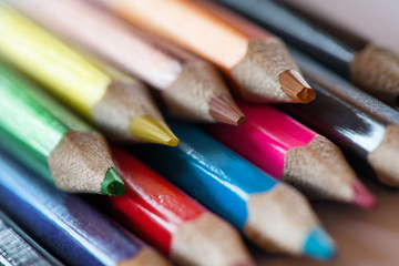 Fototapeta premium Pile of sharp coloured drawing pencils on table. Rainbow colors red, yellow, blue, green, purple. Concept of art, crafts and kids having fun 