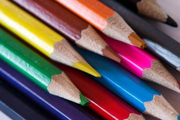 Pile of sharp coloured drawing pencils on table. Rainbow colors  red, yellow, blue, green, purple. Concept of art, crafts and kids having fun
