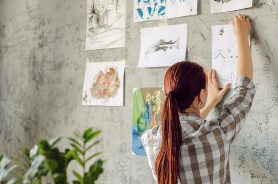 The artist hangs her work on concrete gray wall. Home gallery of works.