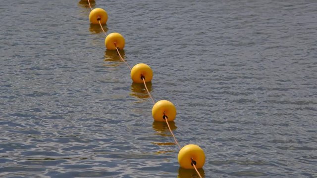 String of Yellow Buoys Floating in the Water to Mark Swimming Area.