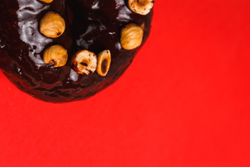 Fototapeta na wymiar Chocolate donut with hazelnutred on a red background