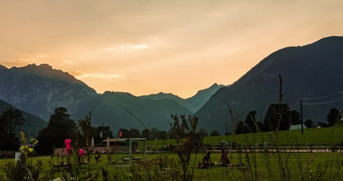 Timelapse of setting sun behind Alpine Mountain while children are playing soccer.