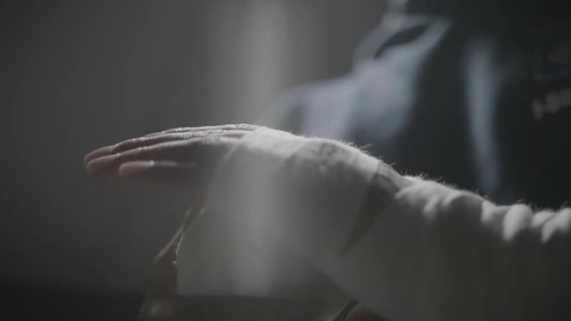 Slow motion of a fighter wrapping his knuckle.