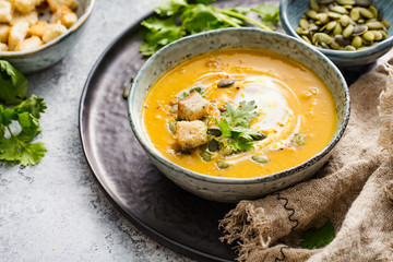 Pumpkin soup in a bowl with croutons and pumpkin seeds.
