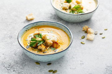 Pumpkin and carrot soup with cream and parsley.