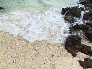 natural sea waves and black rock on the beach with white sand with copy space