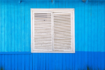 old white wooden blinds on the window and a blue wall around