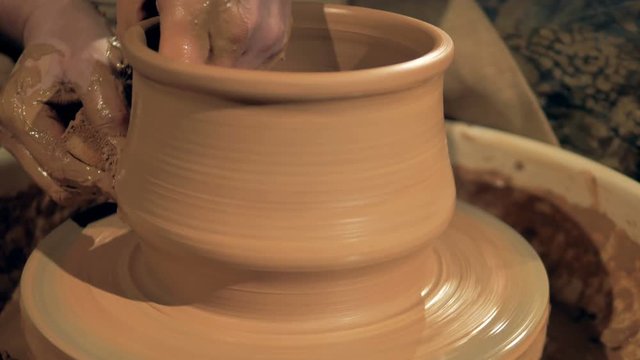 Pottery worker creates a clay vase on a special wheel.