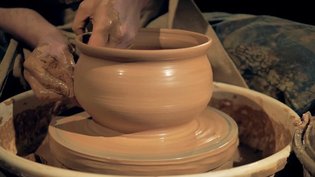 Clay vase turning on a pottery wheel, close up.