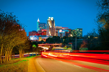 A dramatic skyline of downtown Raleigh, North Carolina at night with light trails.