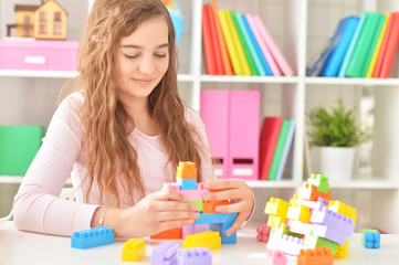 Curly teen girl playing with colorful plastic blocks