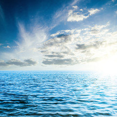 Fototapeta premium sunset in low dark clouds over blue sea