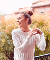Pretty laughing beautiful young woman in white sweater and underwear, standing on balcony. Tuscany, Italy. Small depth of field.