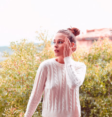 Beautiful young and pensive woman in white sweater and underwear, standing on balcony. Tuscany, Italy. Small depth of field.