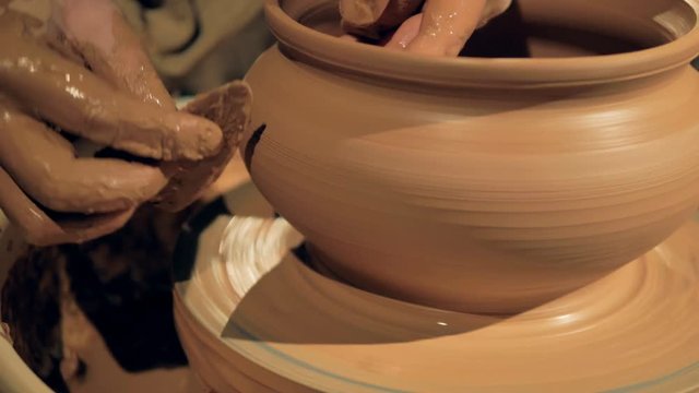 Pottery worker smoothes a vase, close up.