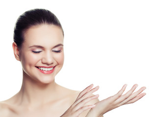 Obraz na płótnie Canvas Young smiling woman showing empty copy space on the open hand isolated on white background. Skincare and wellness concept. Presenting your product