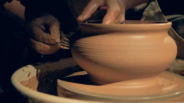 A craftsman shaping a vase with a fork, close up.