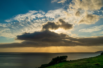 Fototapeta na wymiar Sunset behind some clouds over the sea with orange and blue sky