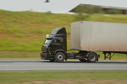 no brand black semi truck going fast on roadway