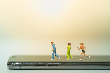 Sport and technology concept. Group of runner miniature figures running on smart phone.