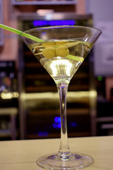 cocktail with alcohol and two olives on a stick on the bar 