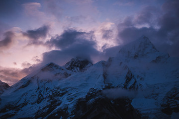 Himalayas landscape. Mountain range with trail in mist and clouds, dark sky with dim sunlight in...