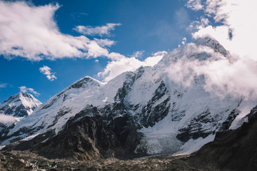 High mountains with snowy peaks in clouds at bright sunny day in Nepal. Colorful landscape with beautiful rocks and dramatic cloudy sky. Nature background. Amazing mountains. Way to Everest base camp.