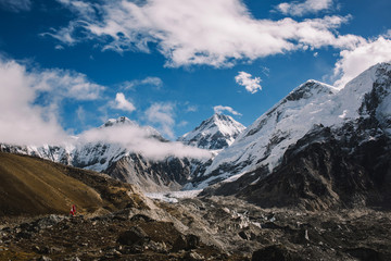 High mountains with snowy peaks in clouds at bright sunny day in Nepal. Colorful landscape with beautiful rocks and dramatic cloudy sky. Nature background. Amazing mountains. Way to Everest base camp.
