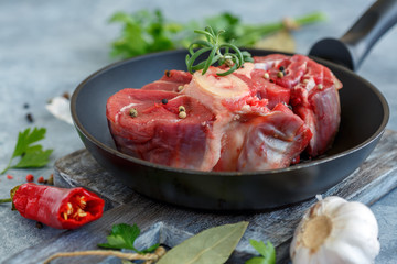 Piece of raw beef shank for Osso Buco and a sprig of rosemary.