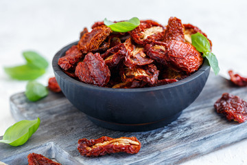 Sun-dried tomatoes in an old wooden bowl. - obrazy, fototapety, plakaty