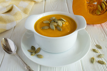 Soup with pumpkin  in the plate on the white wooden background