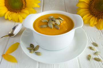 Soup with pumpkin  in the plate on the white wooden background