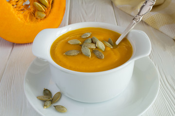 Soup with pumpkin  in the plate on the white wooden background.Closeup.