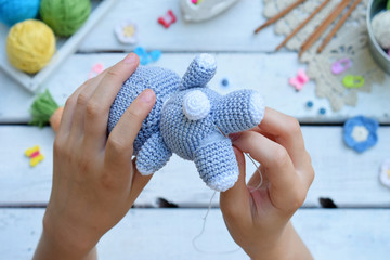 Making rabbit with carrot. Crochet bunny for child. On table threads, needles, hook, cotton yarn....