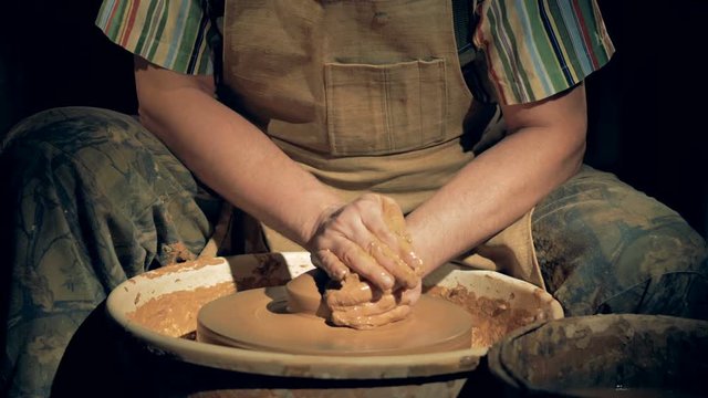 Process of clay molding, close up. A pottery worker presses clay while turning it on a special wheel.