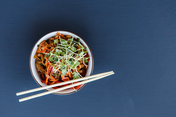 A plate with wok vegetarian noodles with microgreen on the dark background