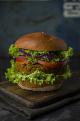 Vegan burger with fresh vegetables on rustic background
