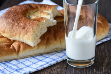 Rustic style. Milk is poured into a glass, bread on a kitchen towel