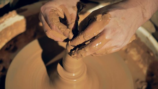 A potter touches clay on a wheel, close up.