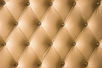 Beige soft textile background with symmetrical buttons on the corners of diamonds. Soft and expensive furniture elements. Luxury background