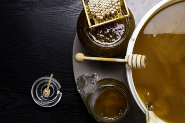 Honey in jar and big bucket, honeycomb and wooden stick