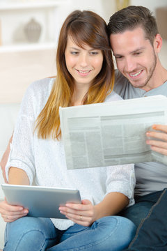 woman with tablet and husband with newspaper